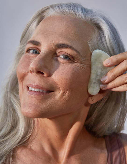 Woman using gua sha on her cheek