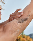 Woman applying body scrub to back of her arm.