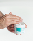 Man holding jar of shaving crème about to grab some out of the jar.