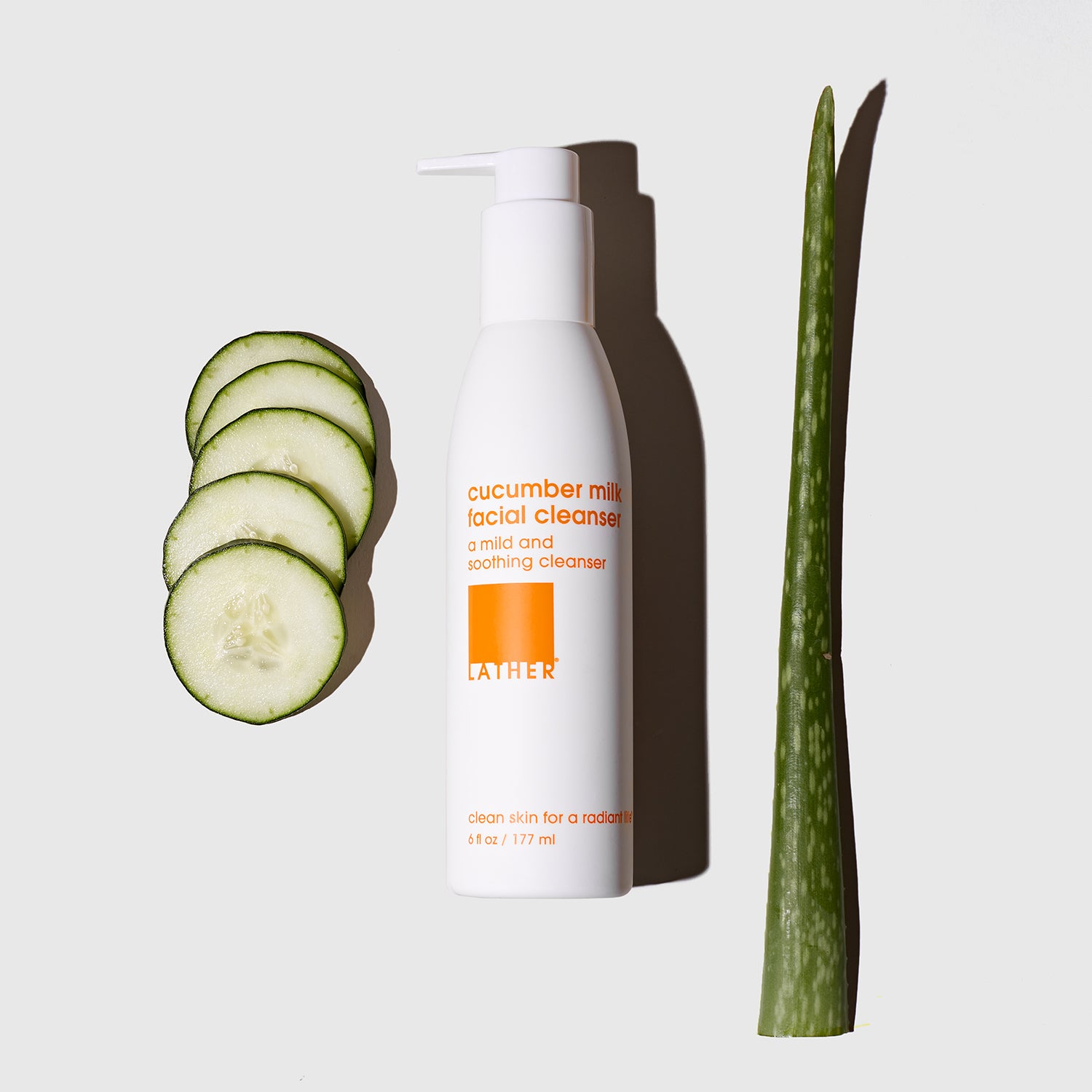 Cucumber Milk Facial Cleanser bottle next to slices of cucumber and a stalk of aloe vera