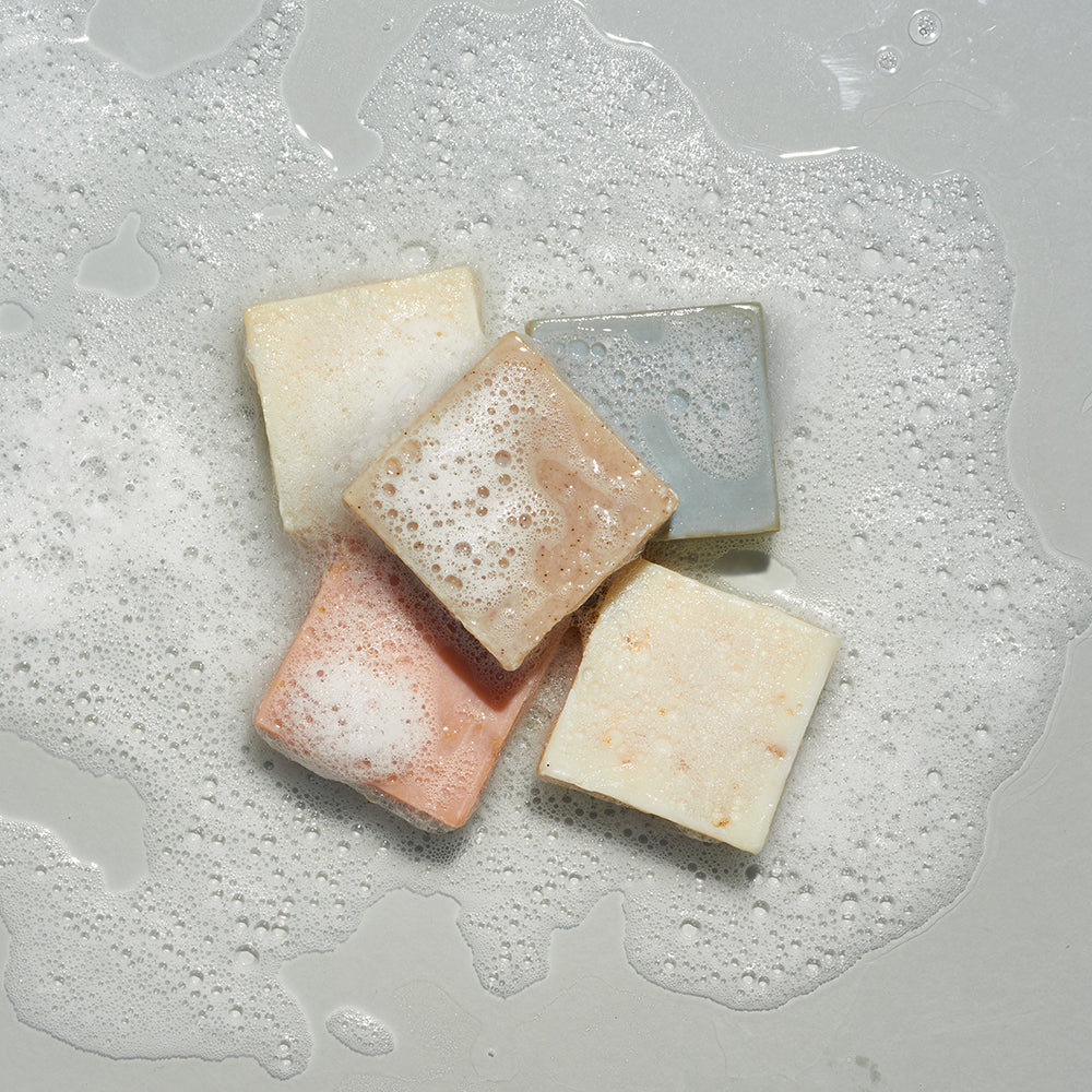 LATHER bar soaps stacked in a sudsy puddle of water